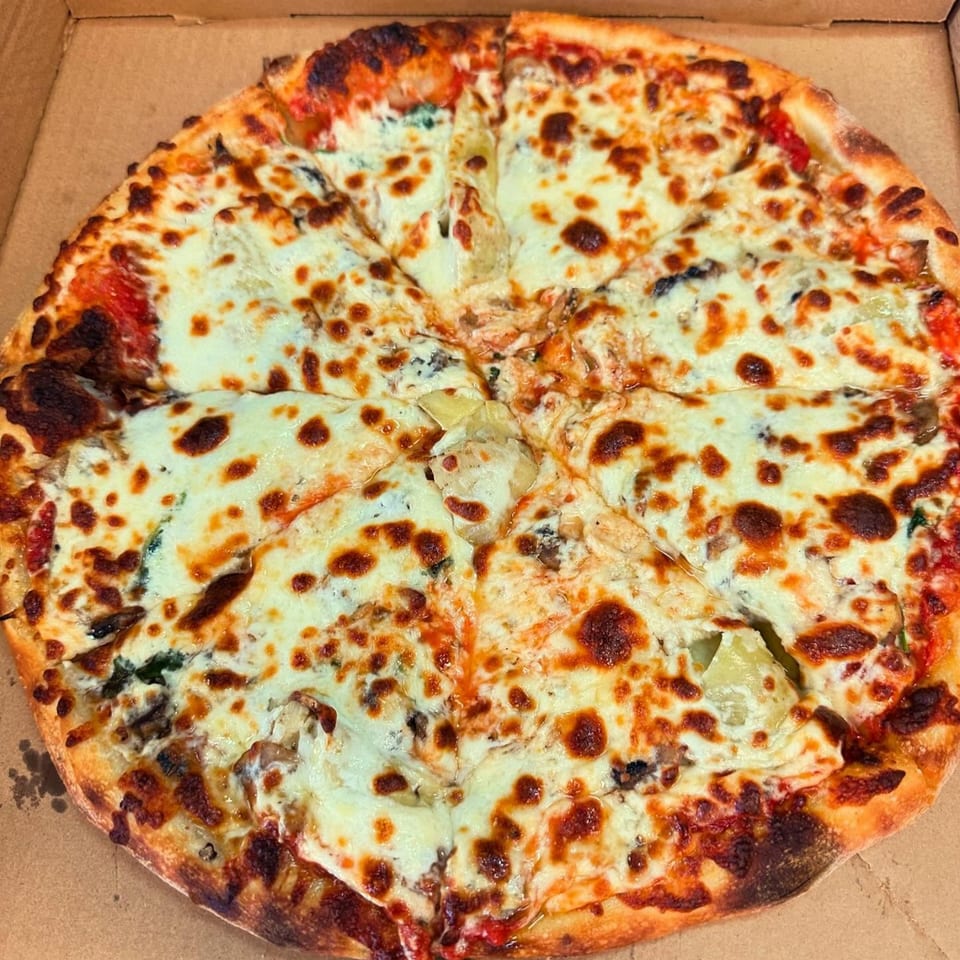 A whole Slice of Martinez pizza, cut into eight slices, with melted cheese and toppings.
